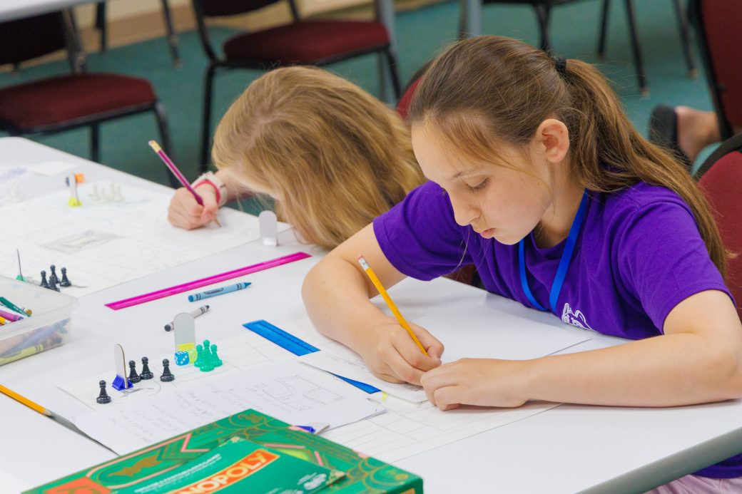 Two summer campers drawing out board game