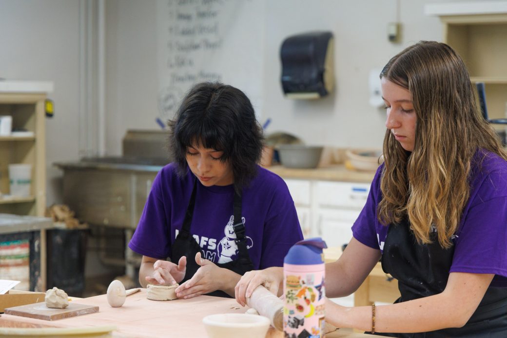 Two female students work on hand modeling clay in summer camp art class