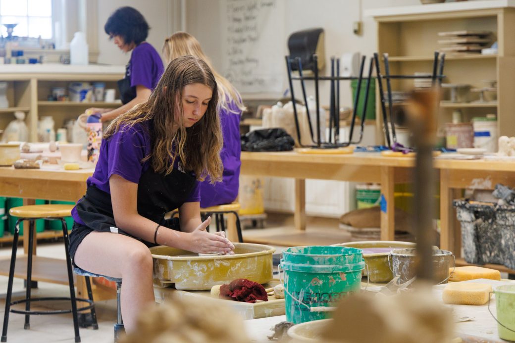 Camper throwing pottery on wheel for summer camp