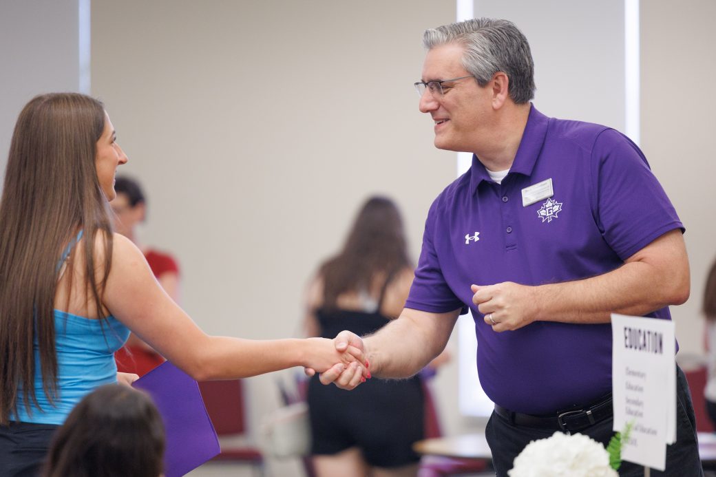 Academic advisor shakes hand with incoming student