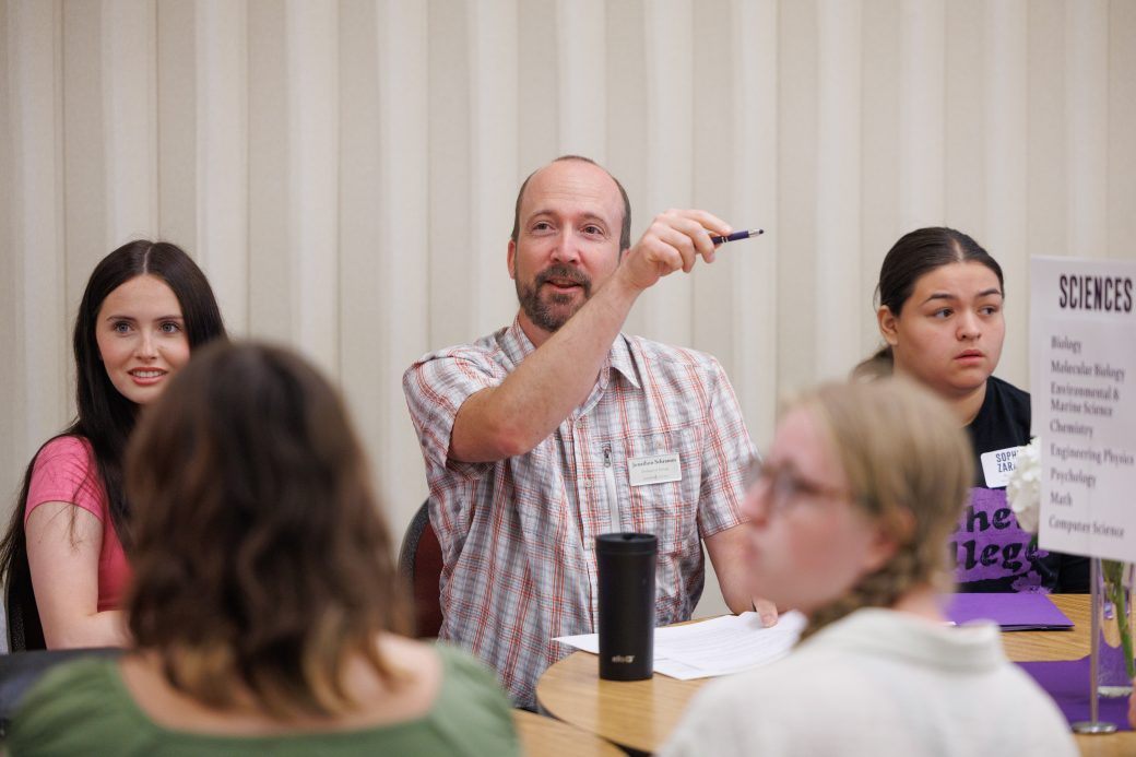 Academic advisor points to an open chair for new student ot sit in