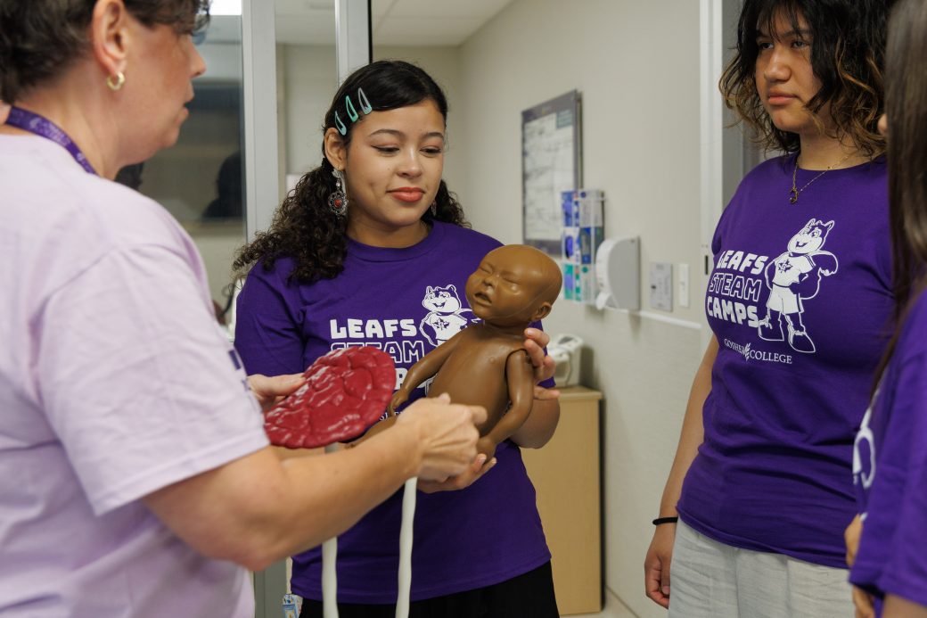 Nursing teacher handing camper baby mannequin