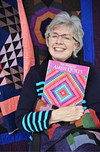 Rebecca Haarer holding a book about Amish quilts 