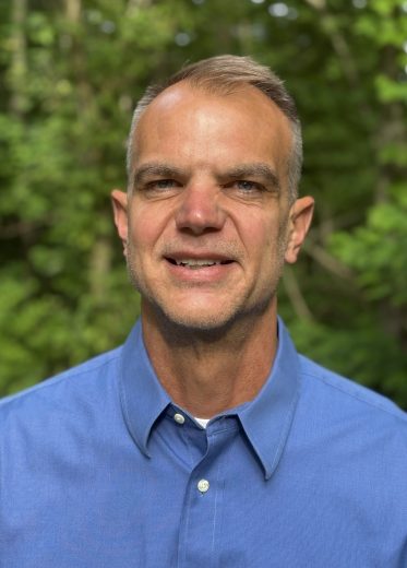 headshot of Jason Kissel wearing a blue button up in an outdoor setting