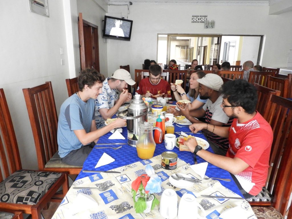 A group of students sharing a meal together around a long table at a restaurant.