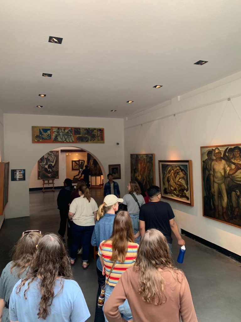 Students looking at artwork displayed in a museum gallery.