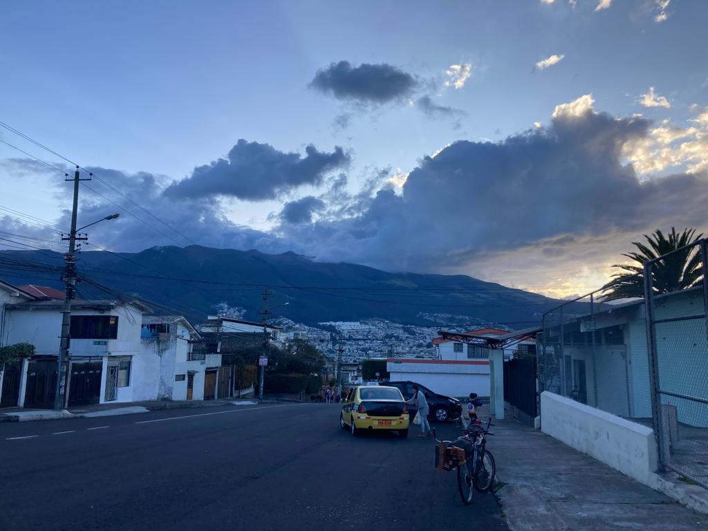A town street lined with buildings beneath cloud-covered mountains.