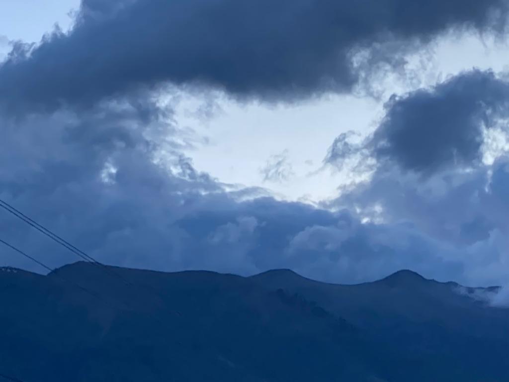Layered mountain ridges under a cloudy sky at dusk.