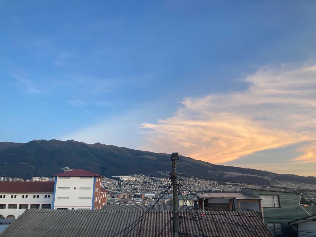 A quiet town street with houses and mountains under an evening sky.