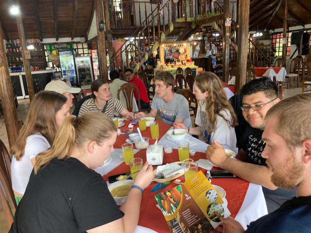 People eating a meal together at a long table in a rustic dining space.