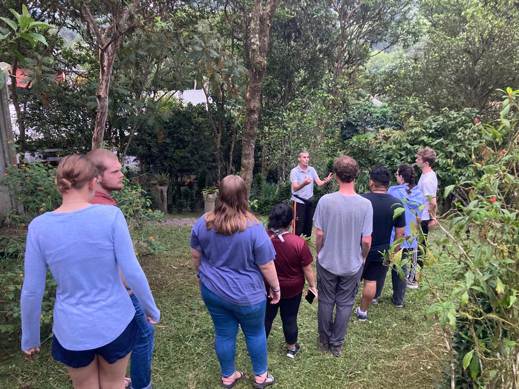 People standing among rows of seedlings under a covered nursery.