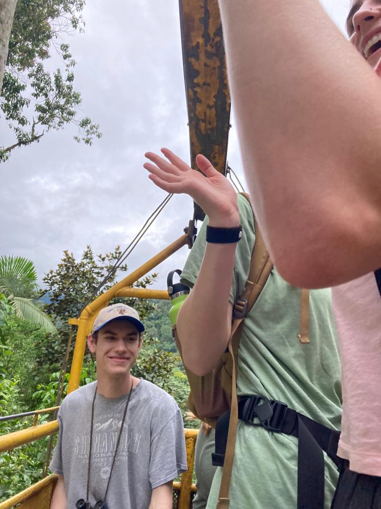 A young man standing beside a yellow cable car platform with another person.
