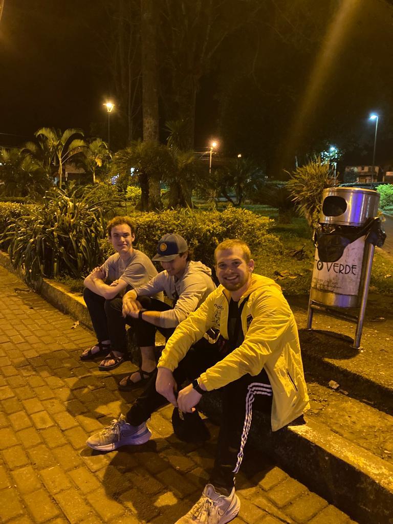 Two people sitting outdoors on a city street at night.