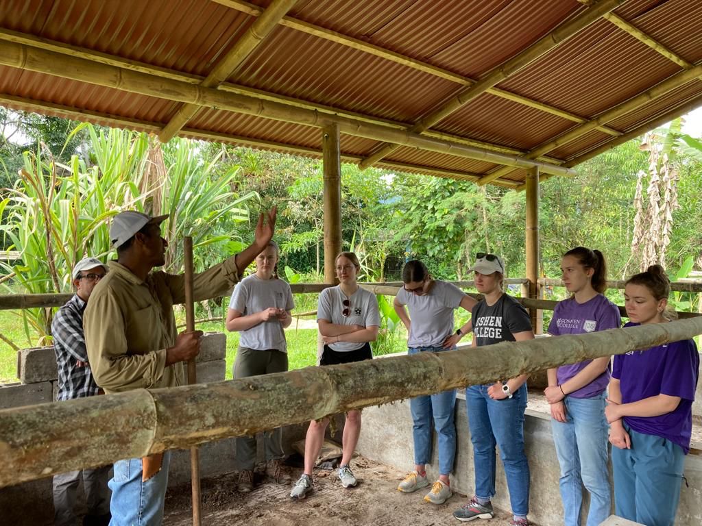 A group of students working under a covered outdoor shelter at a farm.