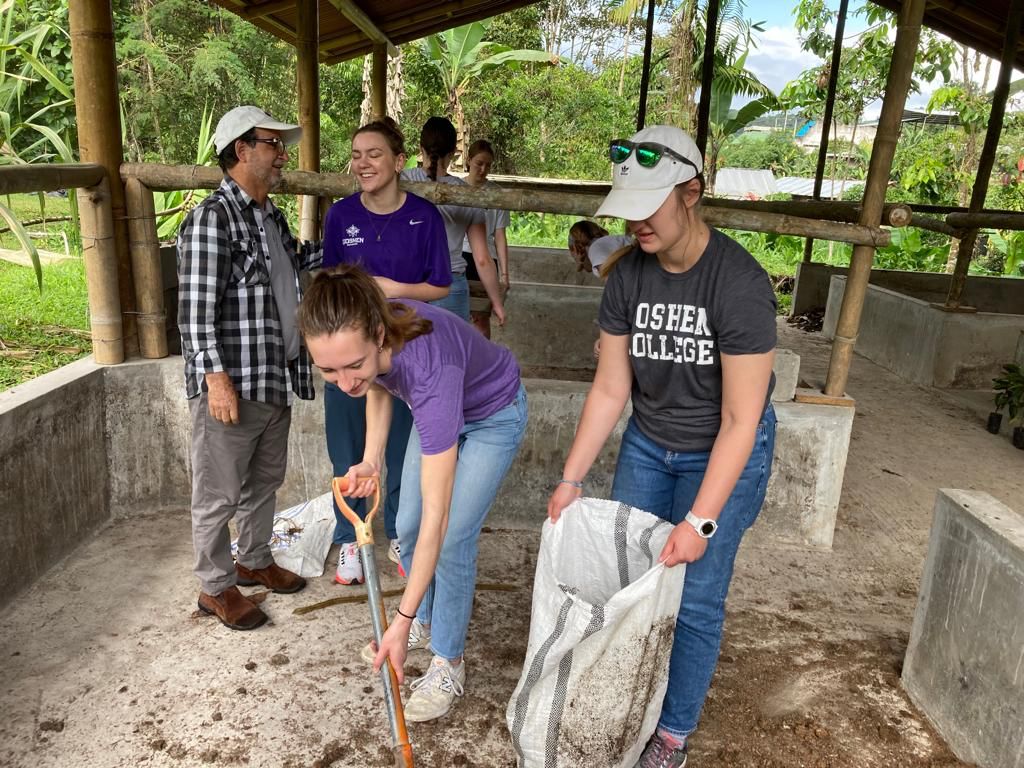 Students shoveling and bagging soil at an outdoor work area.
