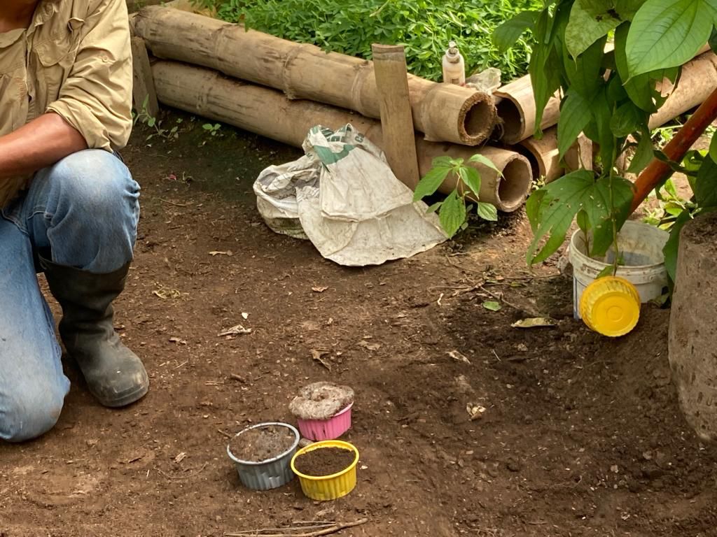 A person crouching to work with pots and buckets on the ground.