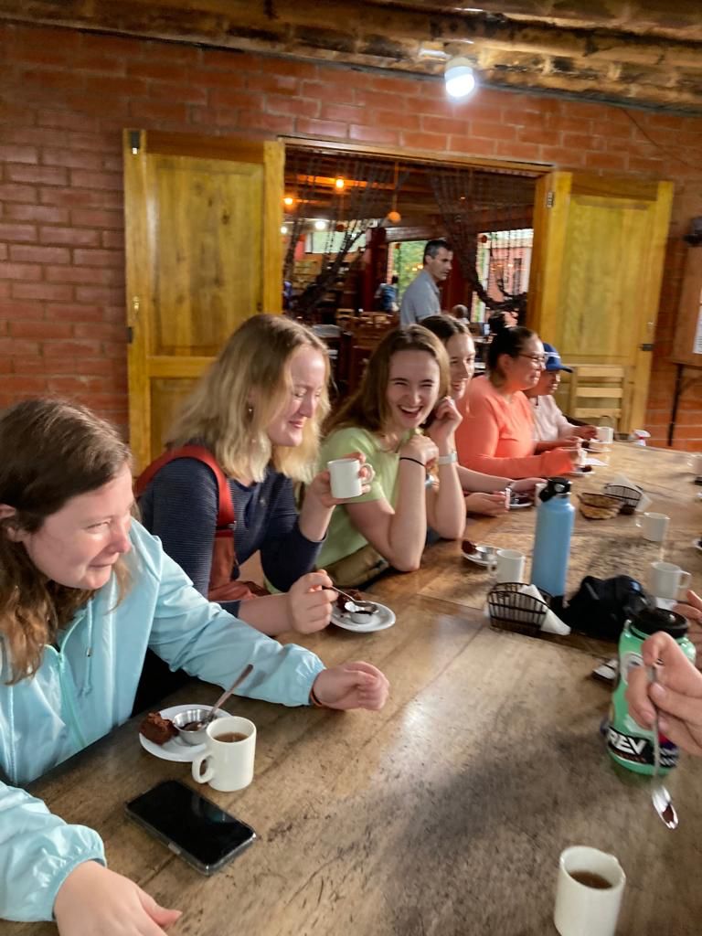 A group gathered around a table talking and enjoying drinks.