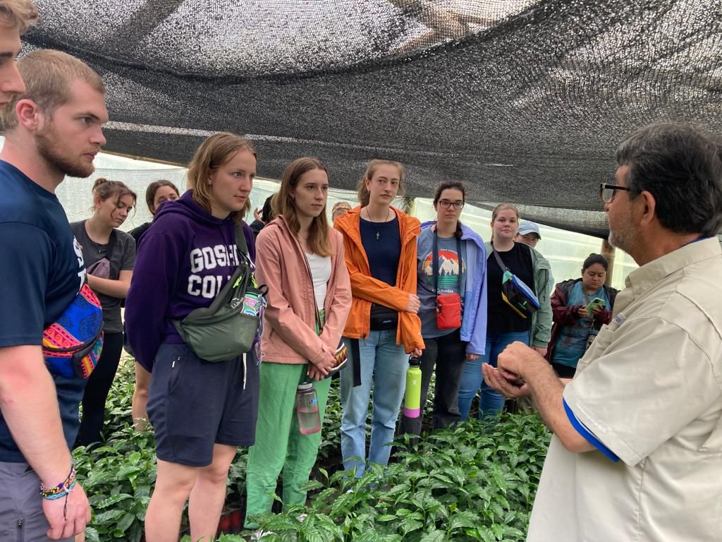 A guide speaking to students under a shaded nursery structure.