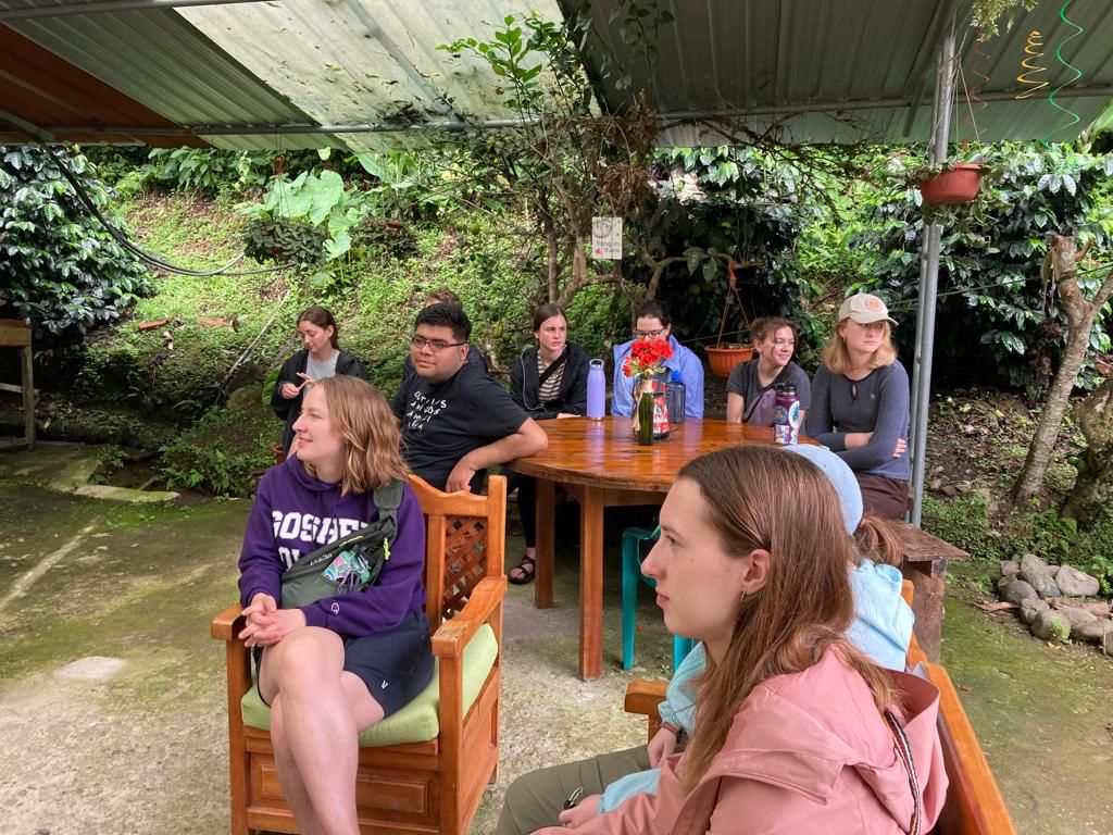 A student relaxing in a chair on a covered patio with others.