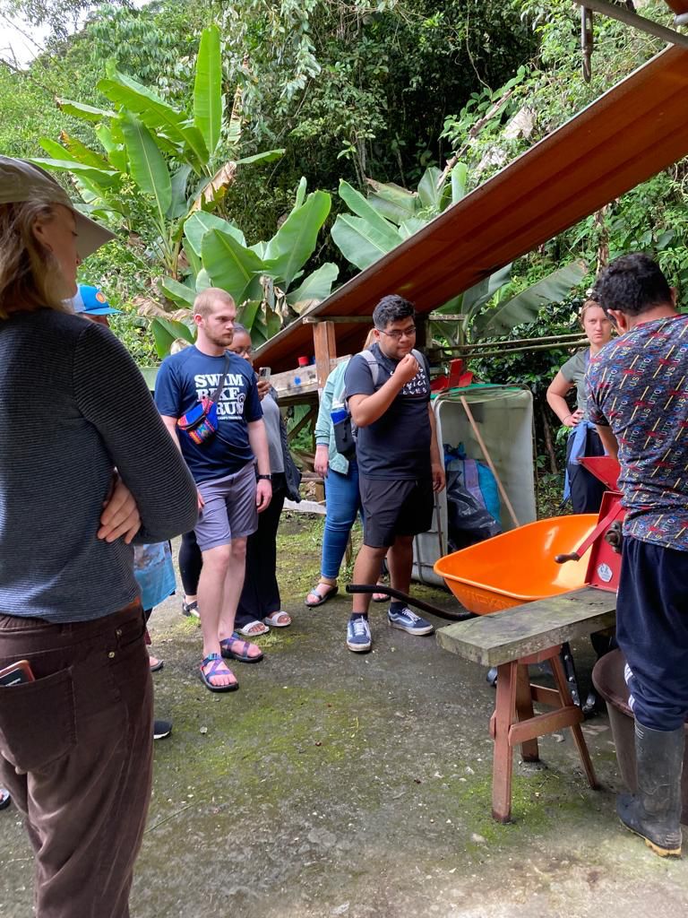People working with buckets and processing machines under a covered area.