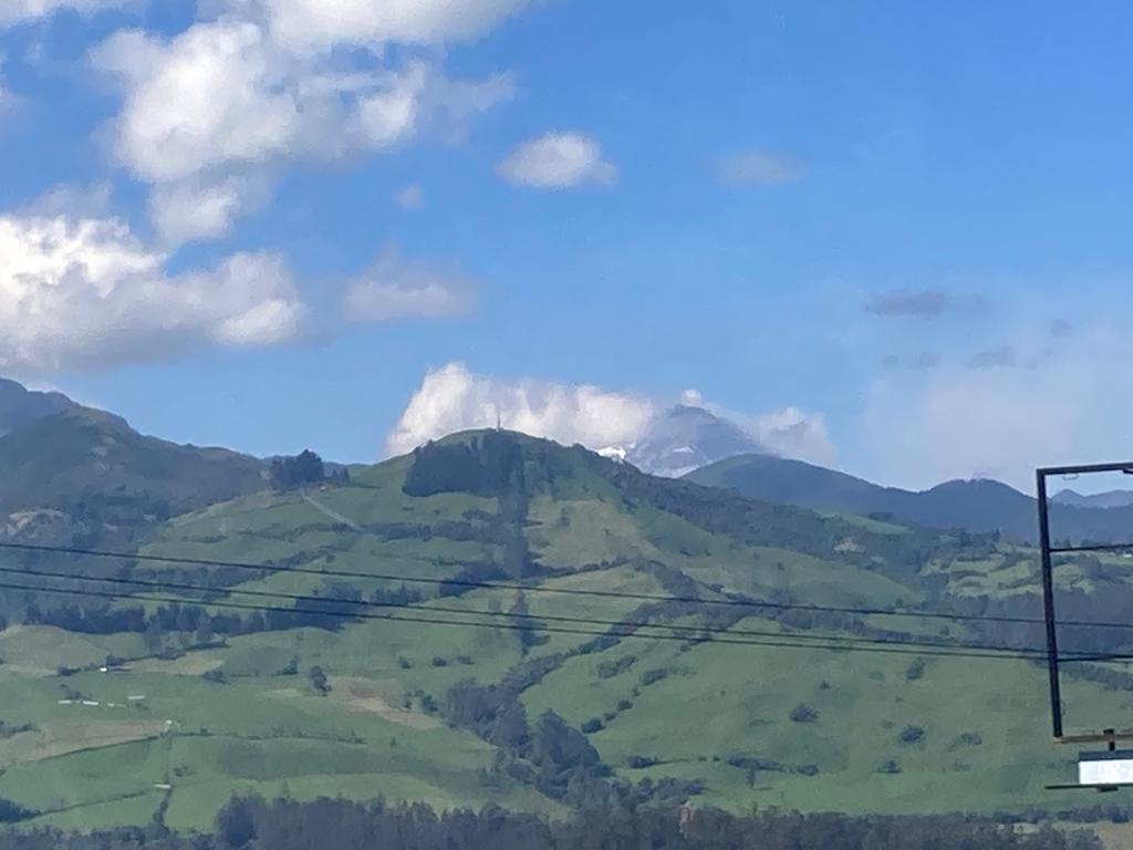 A green mountain landscape with a cloud-topped peak in the distance.