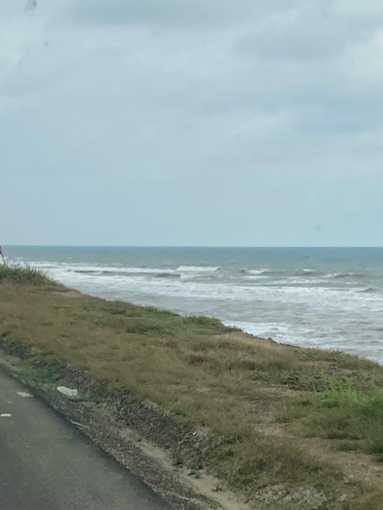 Waves breaking on a shoreline beside a coastal road.