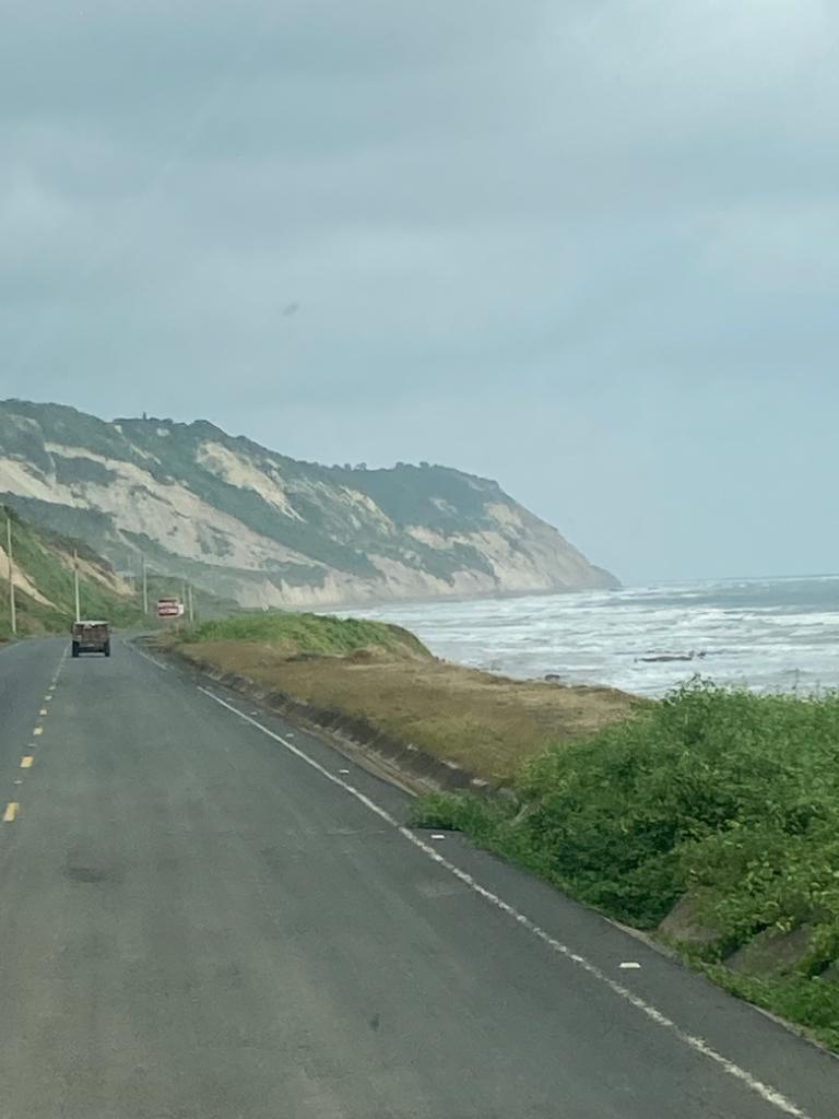 An empty highway running along a cliffside coastline.