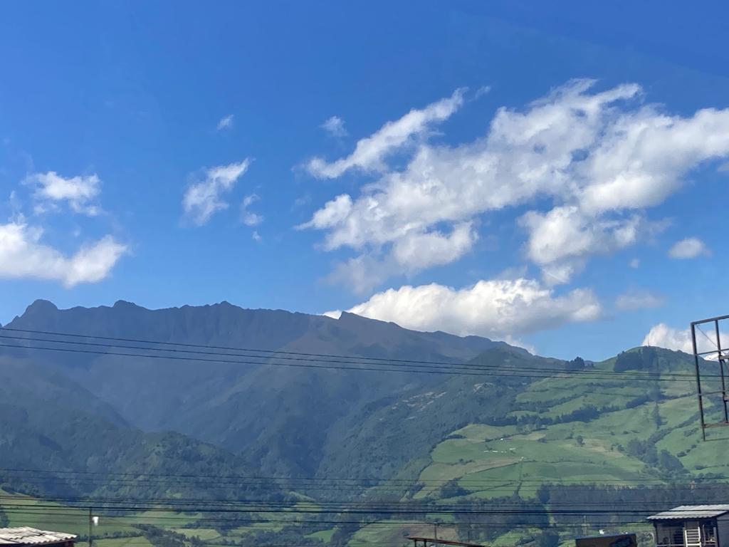 Forested mountains stretching under a blue sky dotted with clouds.