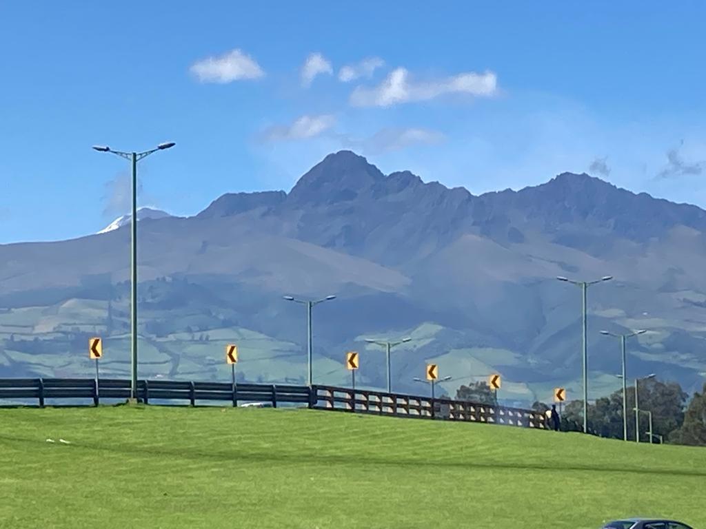 A pointed mountain peak rising beyond a grassy highway.