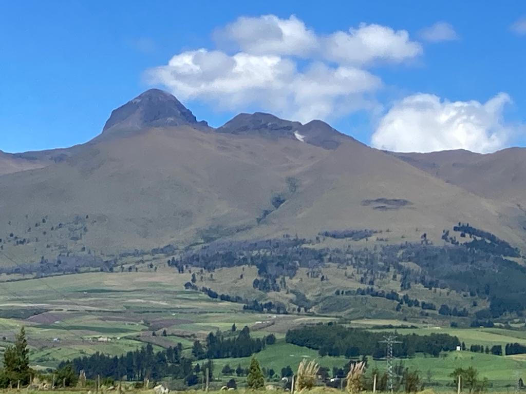 A rugged brown-and-green mountain peak overlooking patchwork farmland.