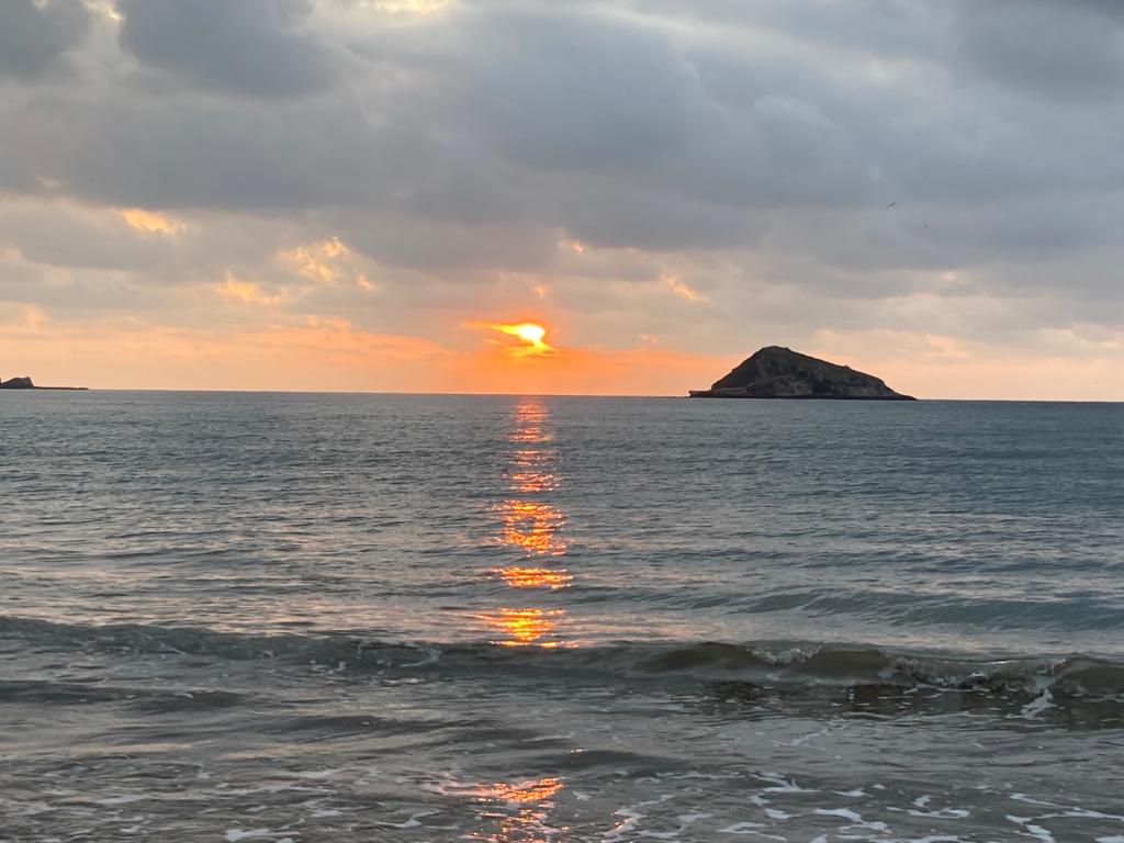 A colorful sunset sky over the sea beside an islet.
