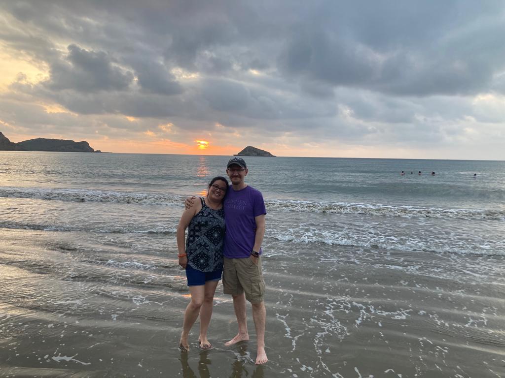 A couple posing together on the beach at sunset.