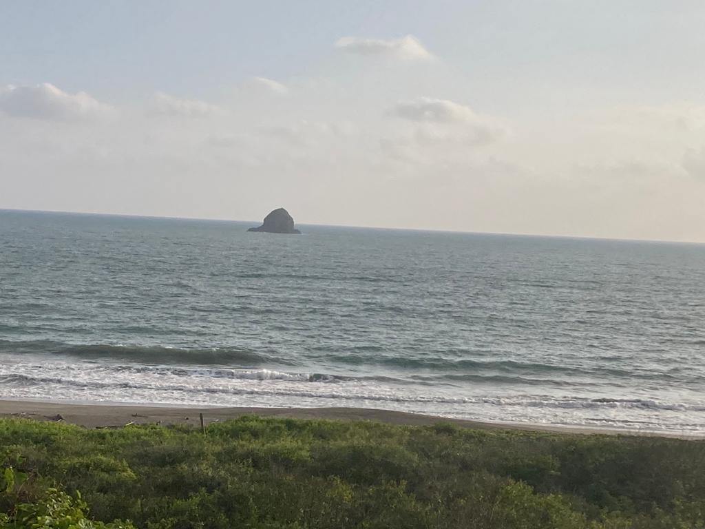 An ocean view with a small rocky islet offshore.