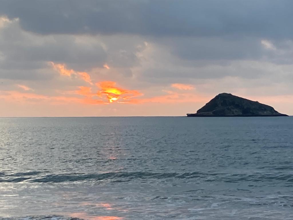 A dramatic cloudy sunset reflected on the wet beach.