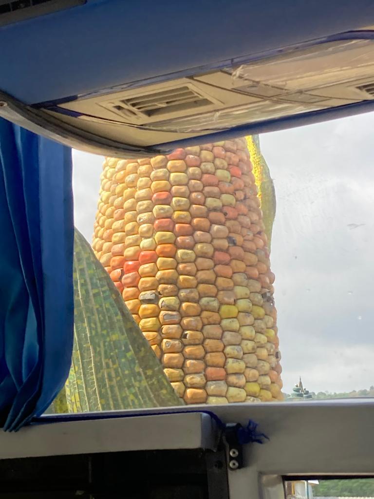 A giant corn-cob monument seen through a bus windshield.