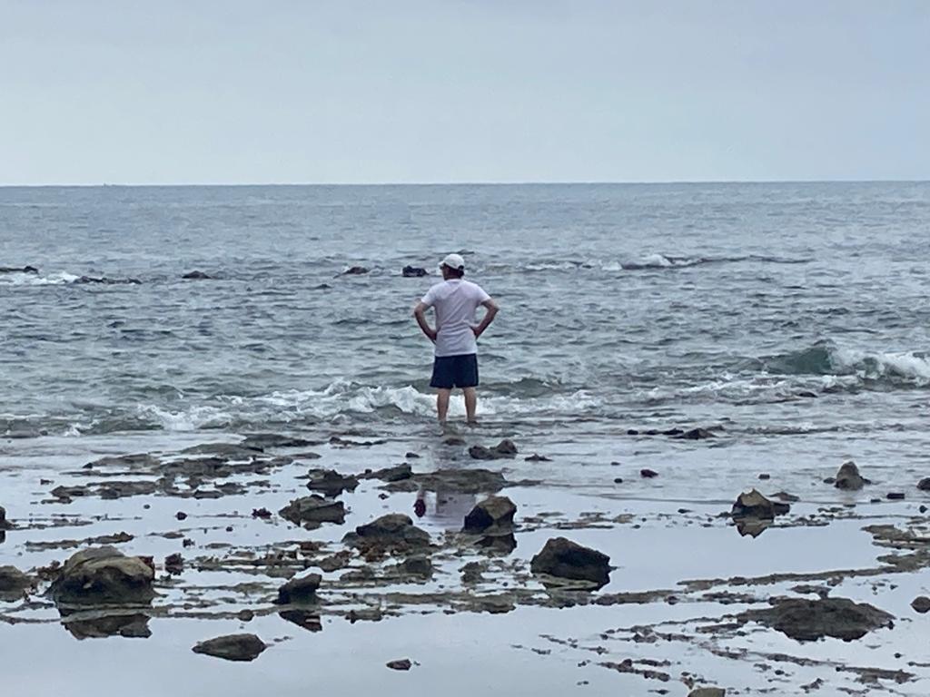 A person standing on rocks looking out at the sea.