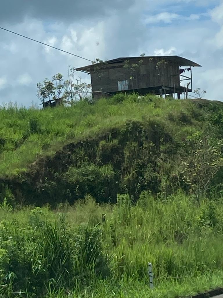 A small wooden stilt house perched on a grassy hilltop.