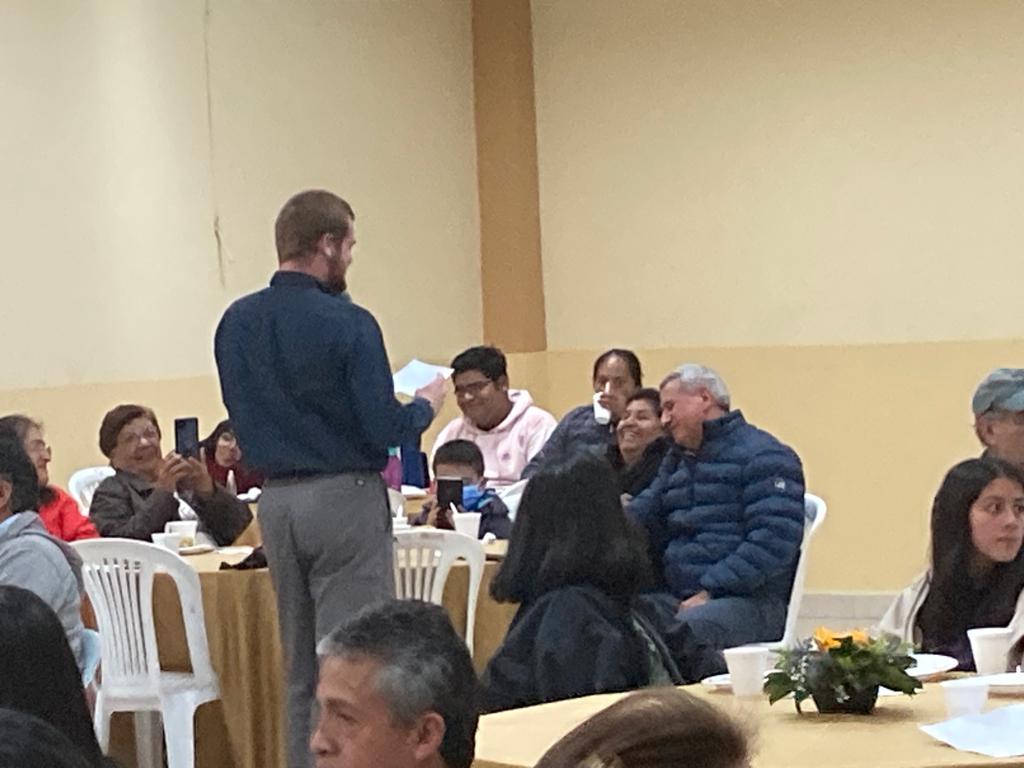 A man speaking to attendees seated at a community event.
