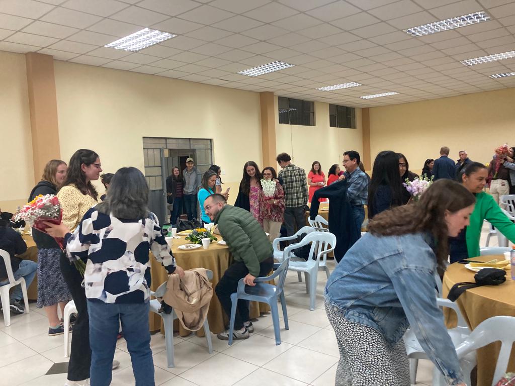 People mingling at tables during an indoor social gathering.
