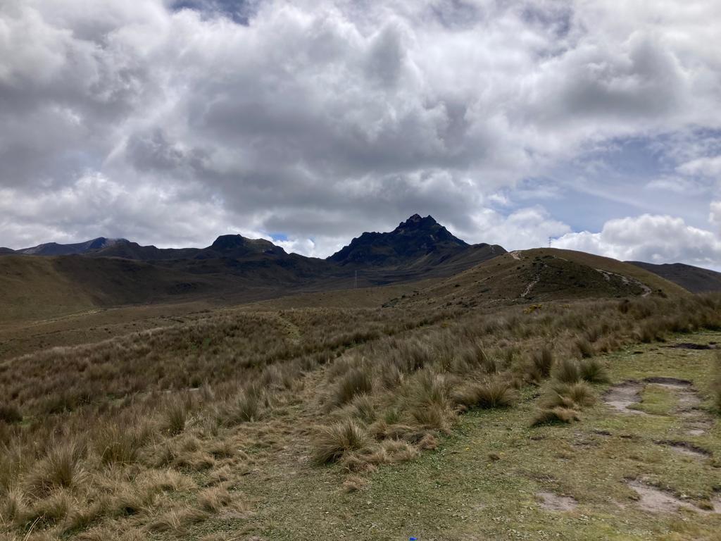 A rugged green mountain ridge under a cloudy sky.
