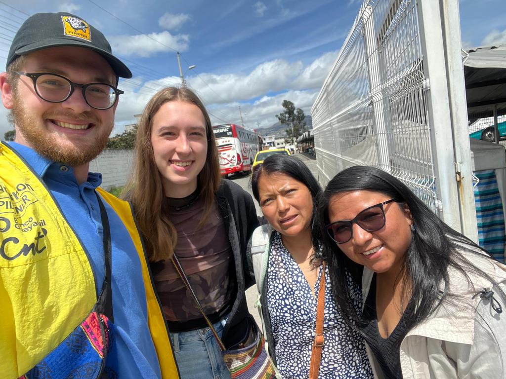Students posing with host family members near a bus.
