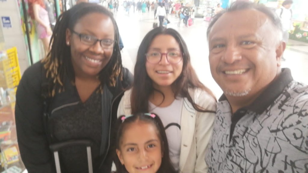 A selfie of a student with host family members and a child.

