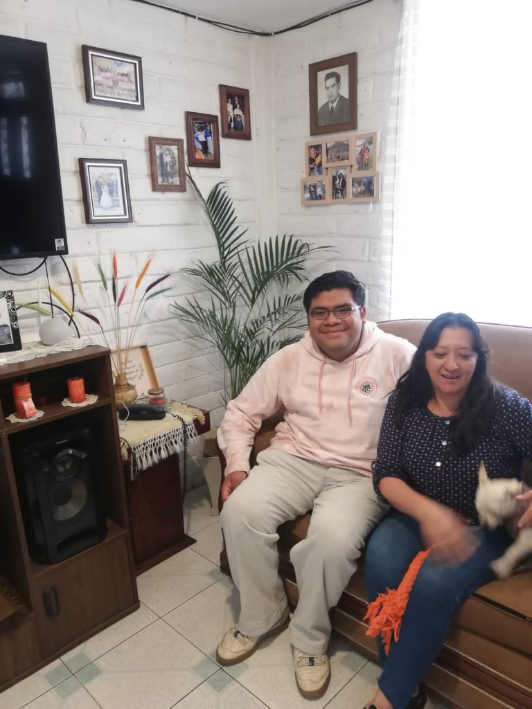 A student seated with a host family member in a home.
