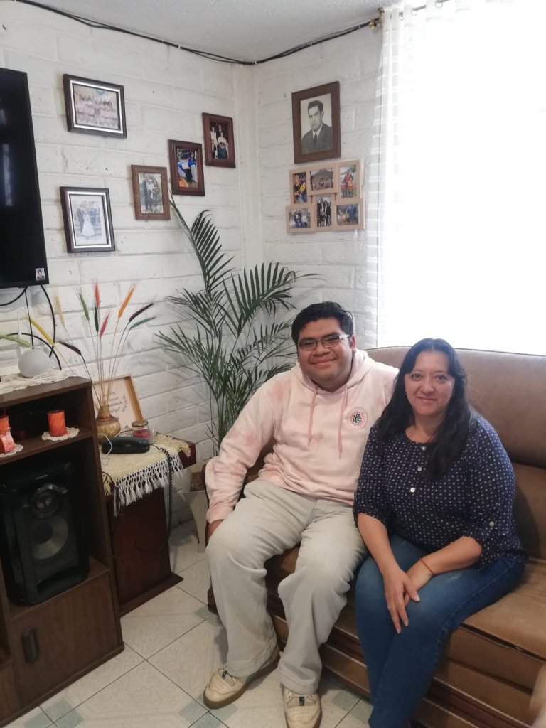 A student seated with a host family member in a living room.
