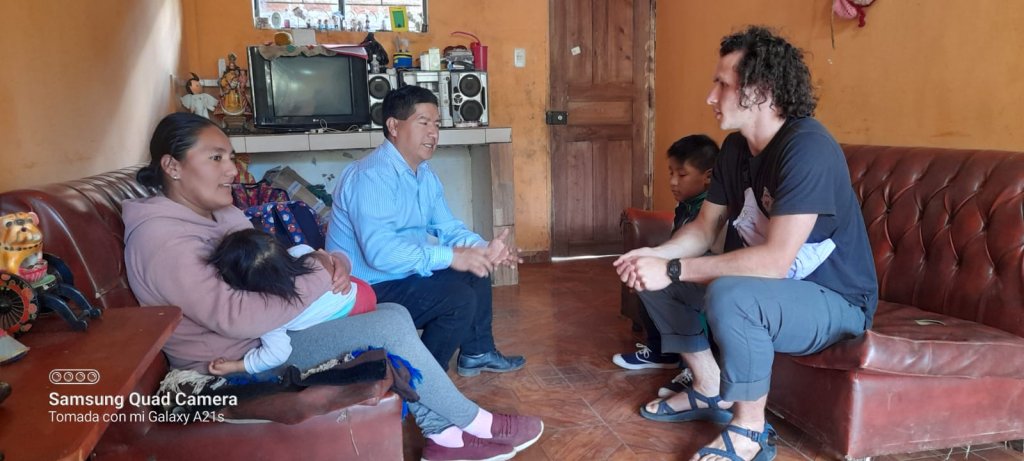 A student and host family conversing in a living room.
