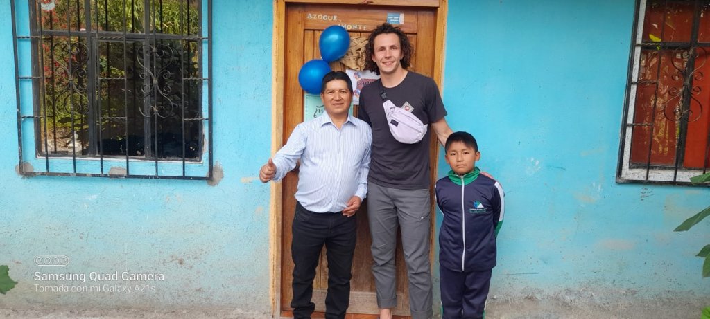 A student posing with a host family outside a blue house decorated with balloons.
