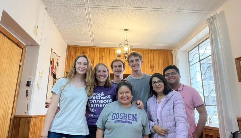A group of students posing together in a bright indoor room.
