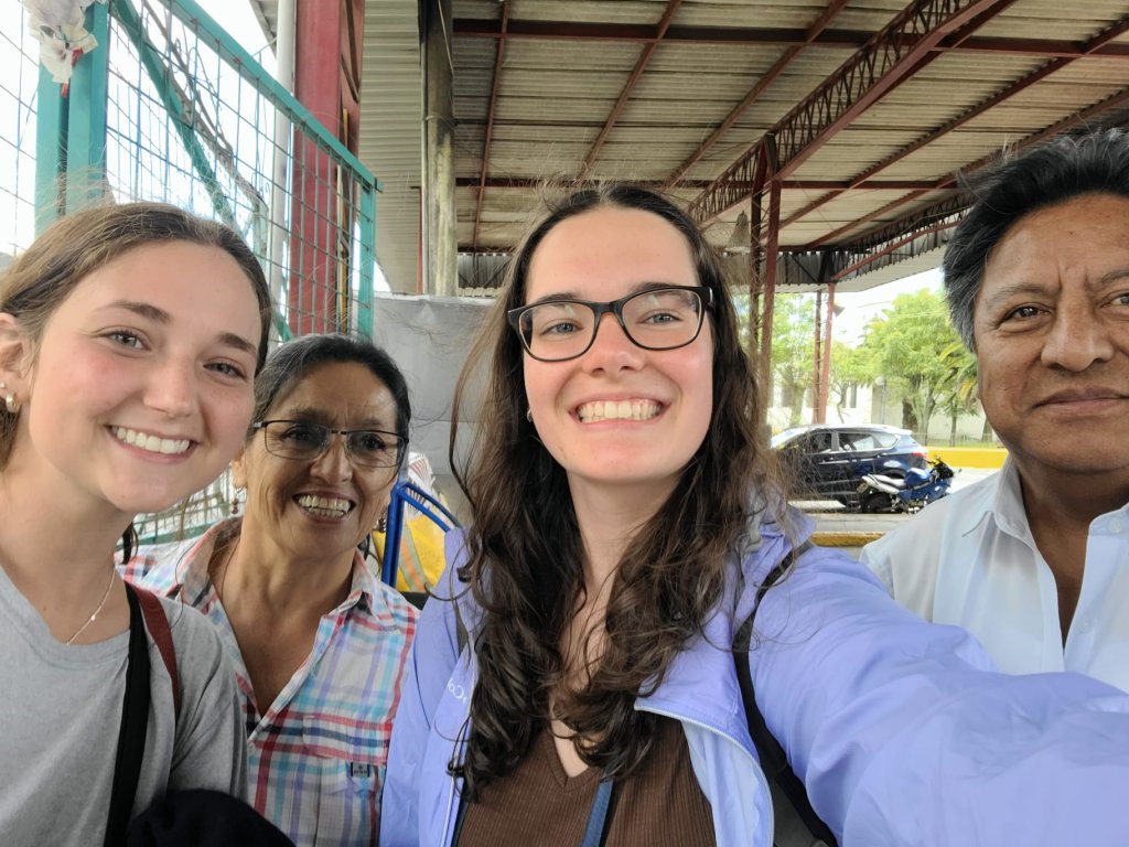 A student taking a selfie with host family members outdoors.
