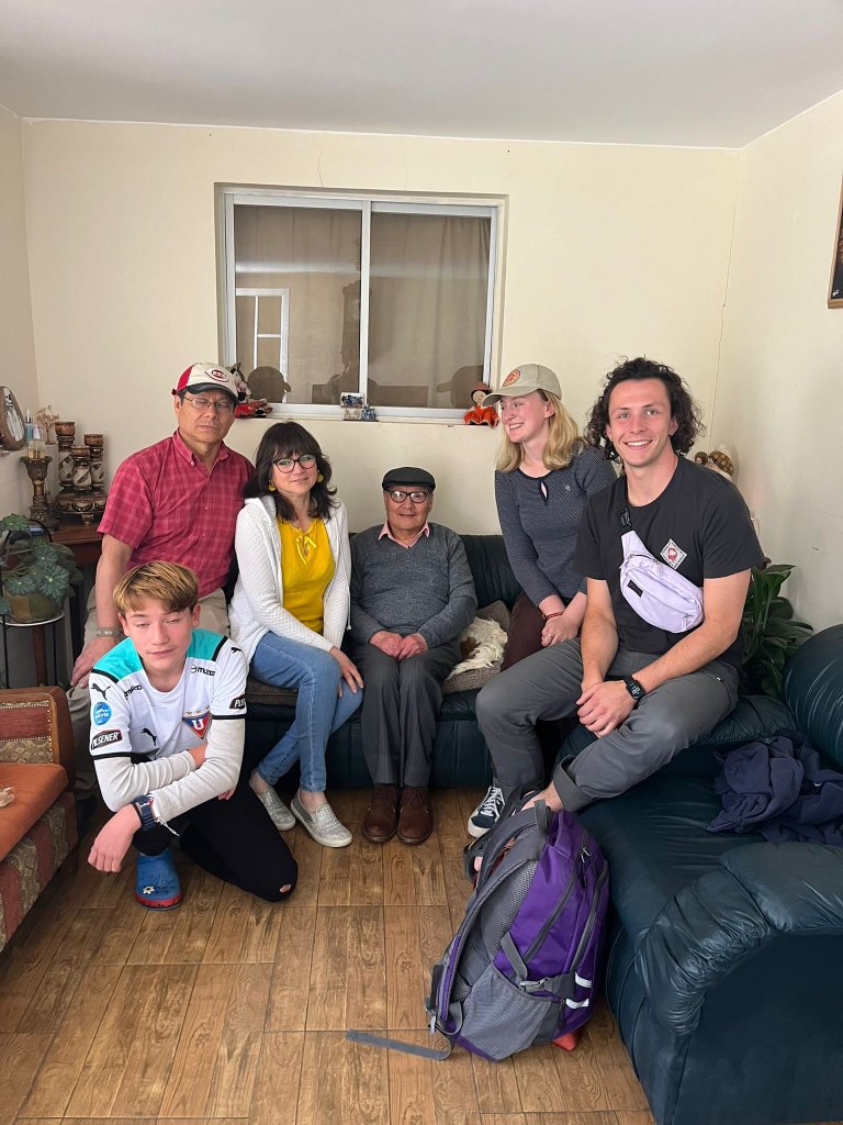 A student posing with a host family in a living room.
