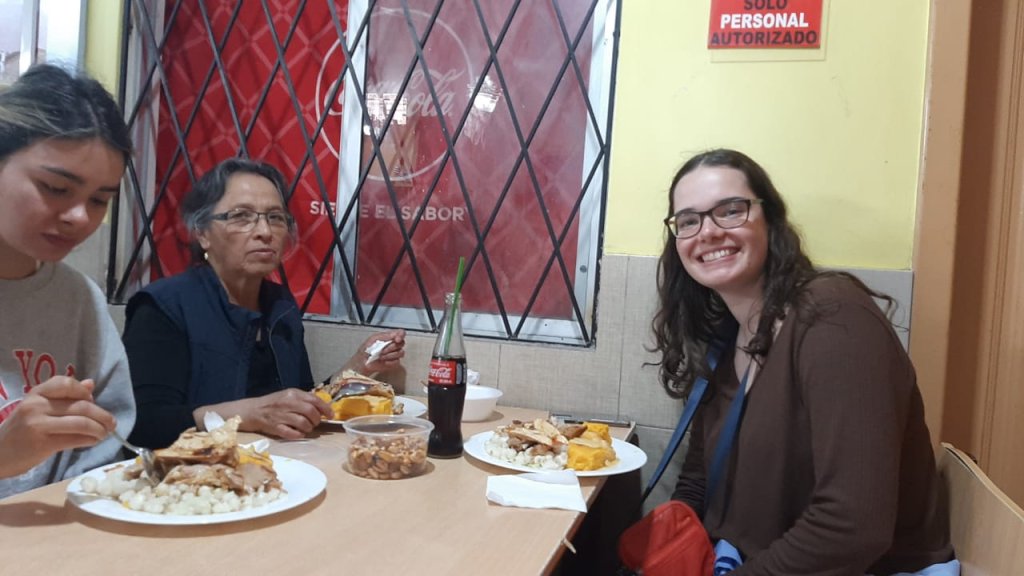 A student sharing a meal with host family members at a restaurant.
